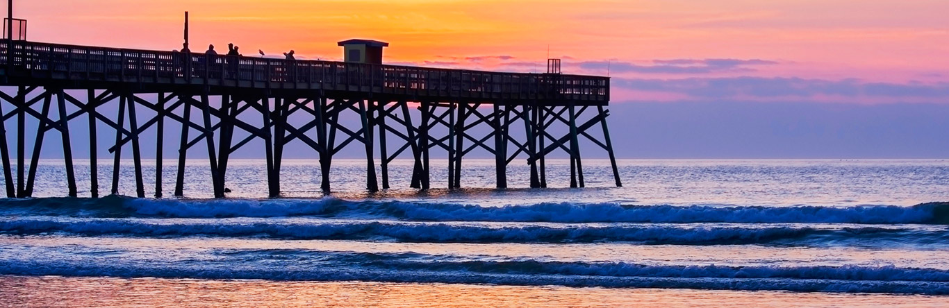 Pier leading into ocean at dusk