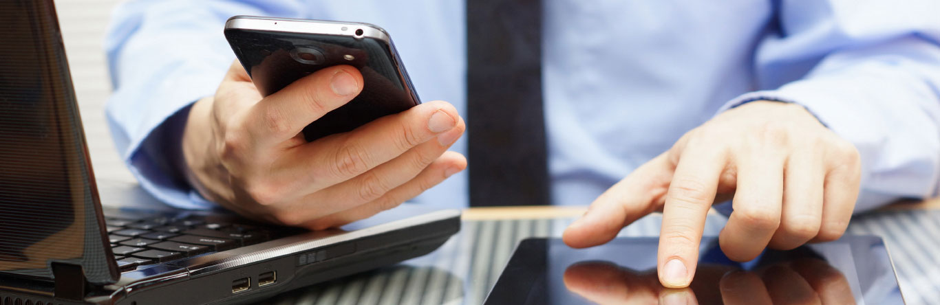 Man using cell phone, laptop computer and tablet